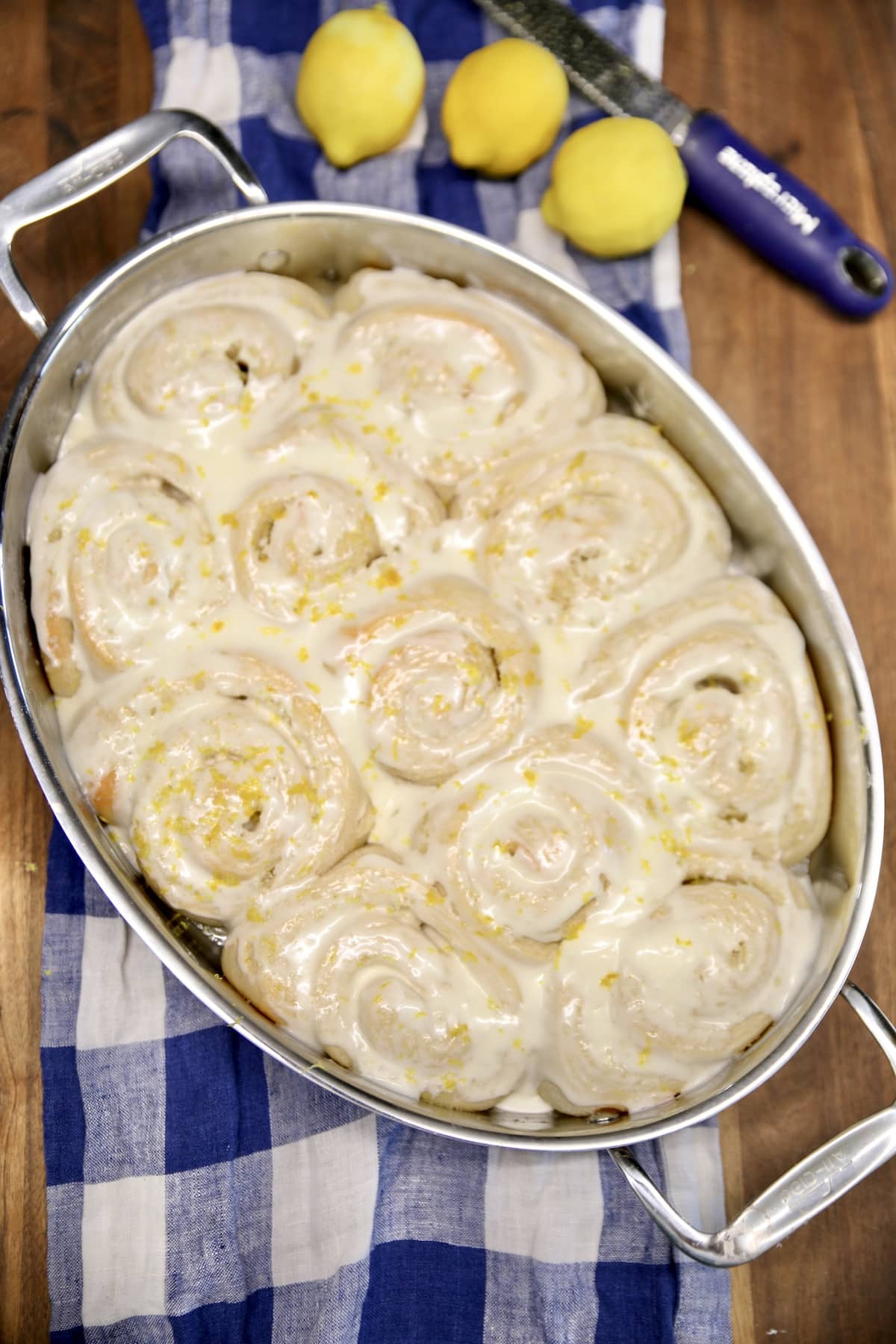 Lemon rolls with cream cheese icing in an oval pan.