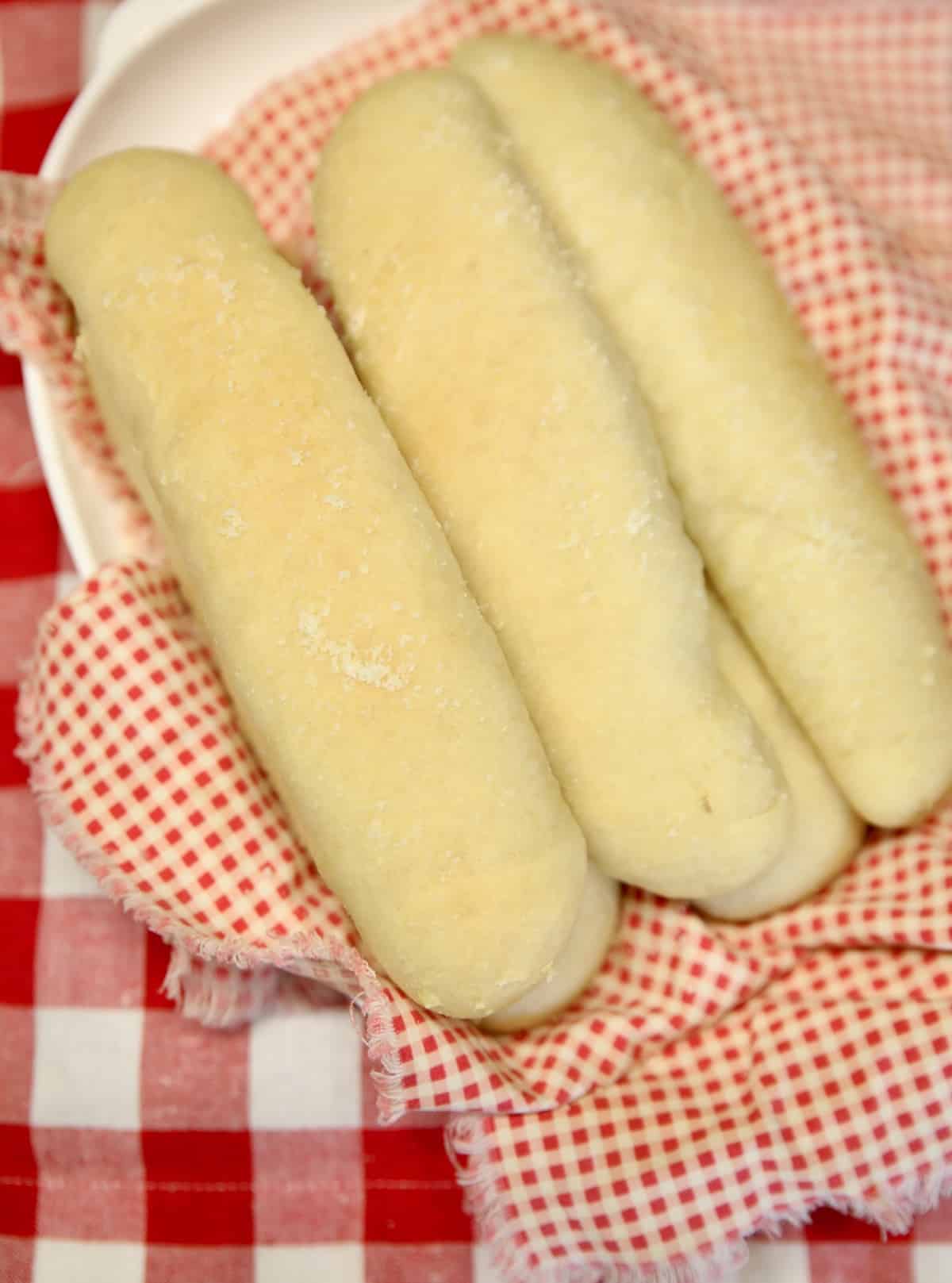 Plate of breadsticks on red check napkin.