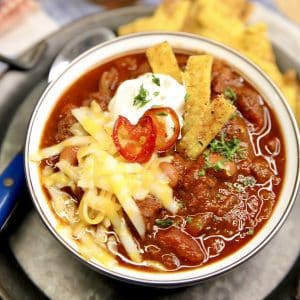 Smoky Chili in a bowl with shredded cheese and candied jalapenos.