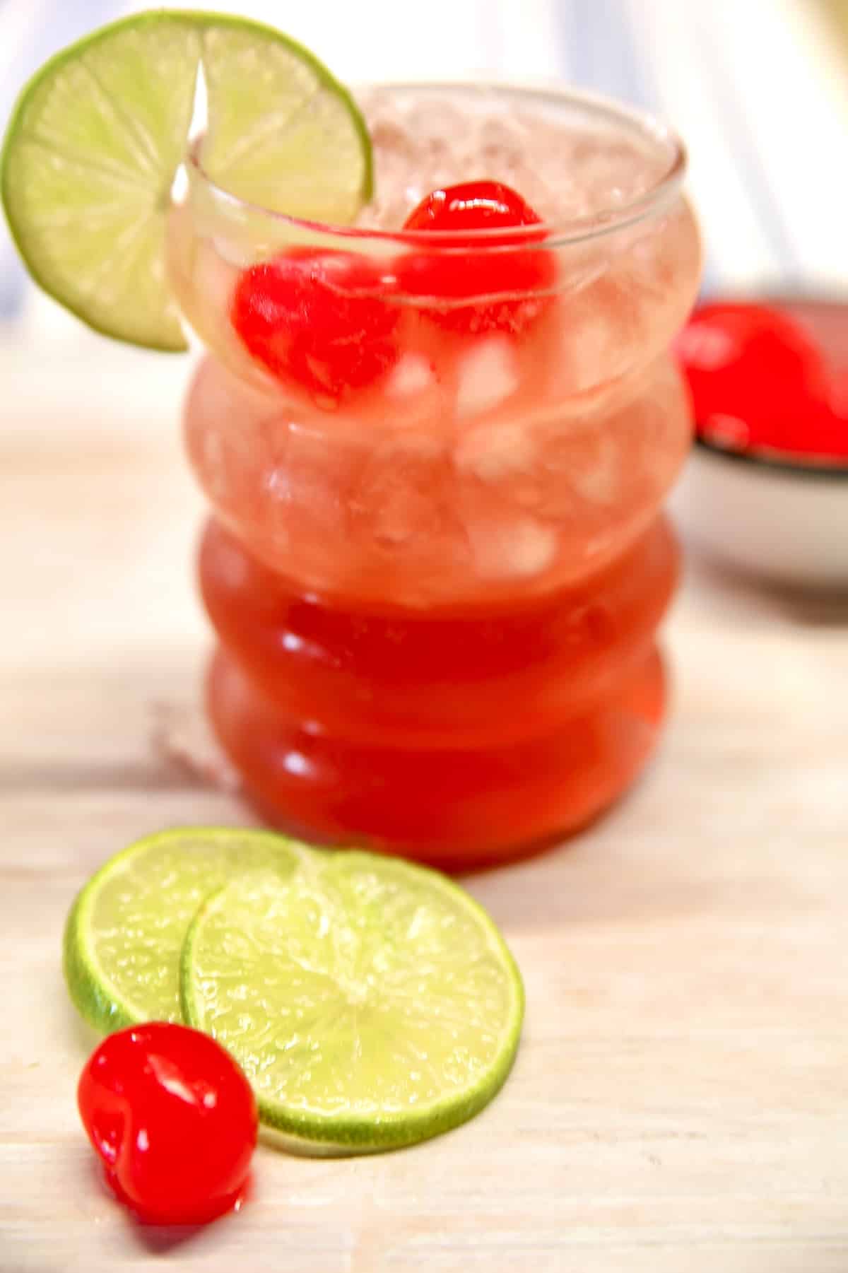 Cherry limeade wine punch in a glass with cherry and lime garnish.