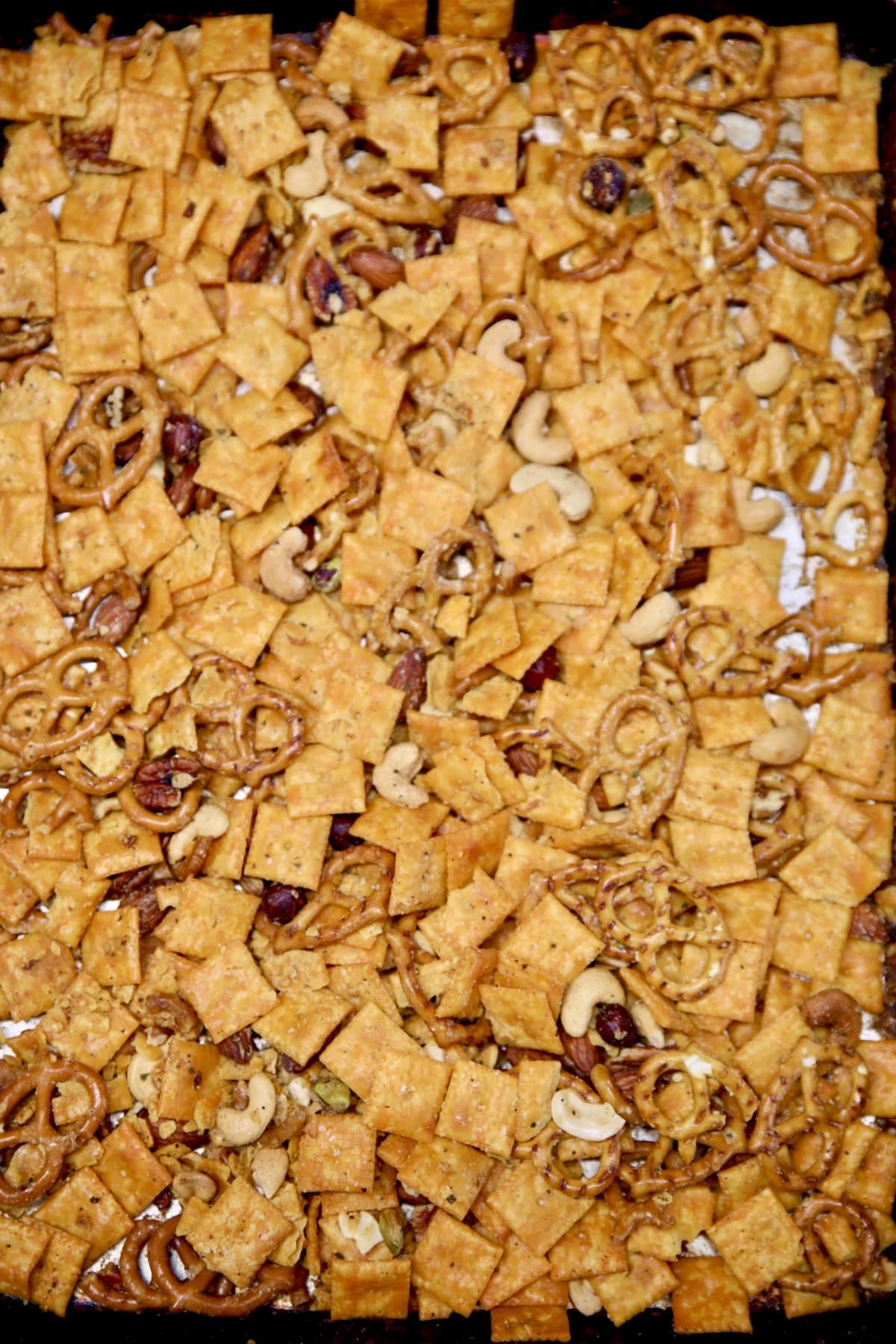 Sheet pan of snack mix with cheese crackers, nuts and pretzels.
