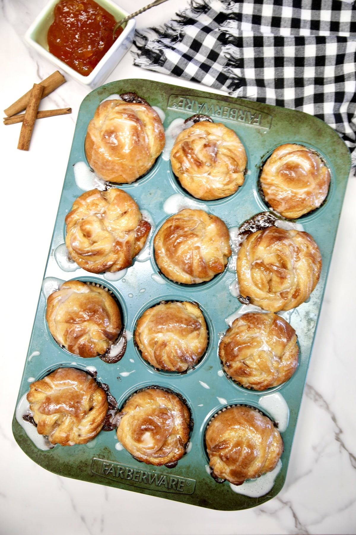 Peach pie cruffins with glaze in a muffin tin. 