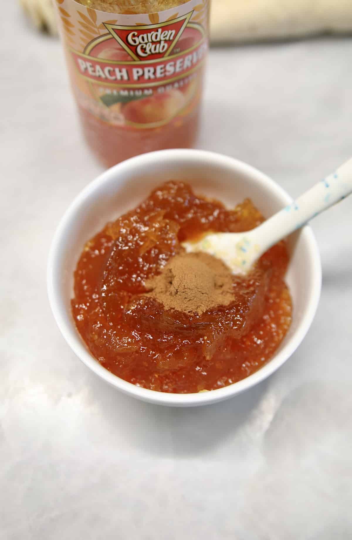 Peach jam in a bowl with ground cinnamon.