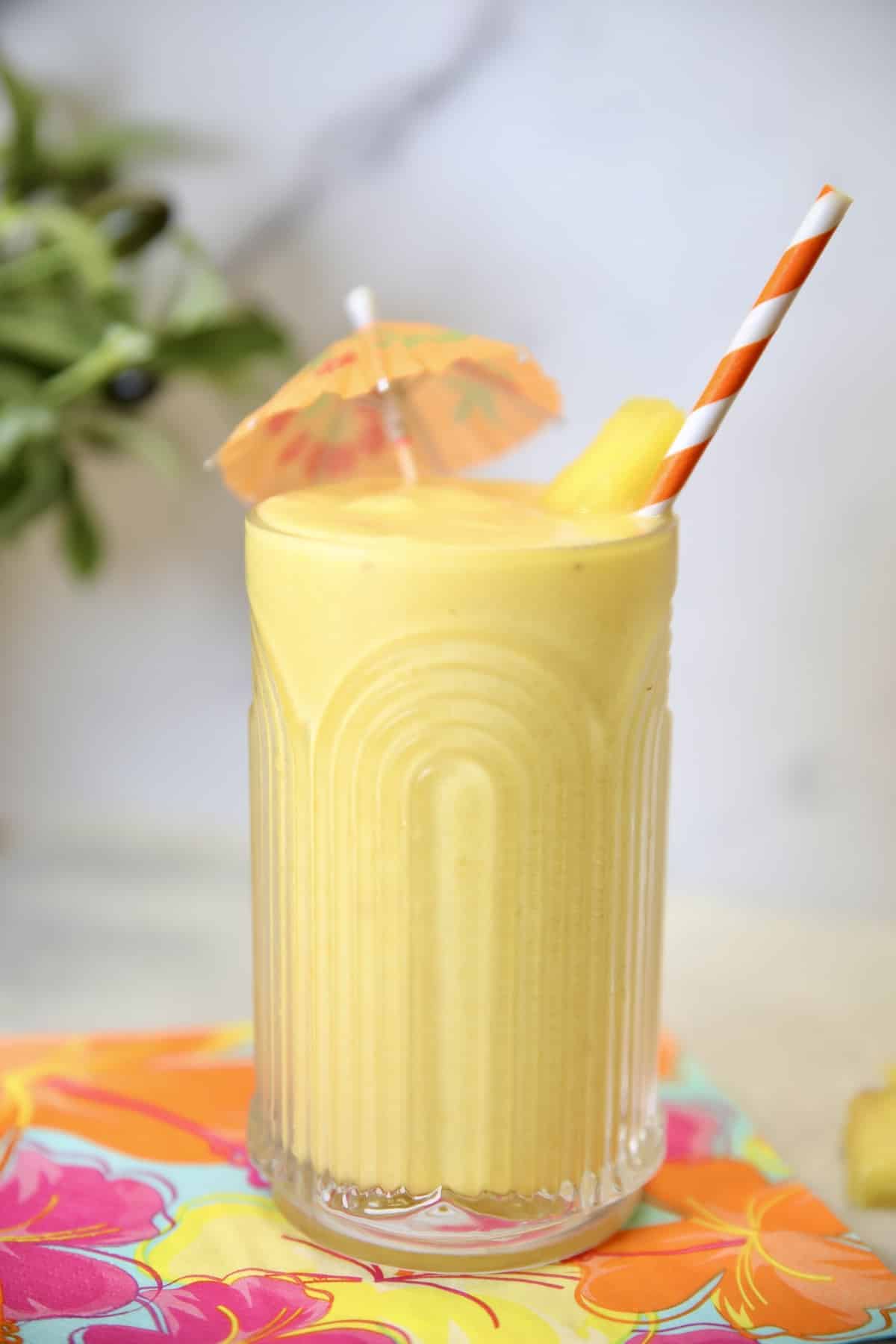 Pineapple smoothie with drink umbrella and straw.