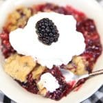 Blackberry crumble in a bowl with whipped cream.