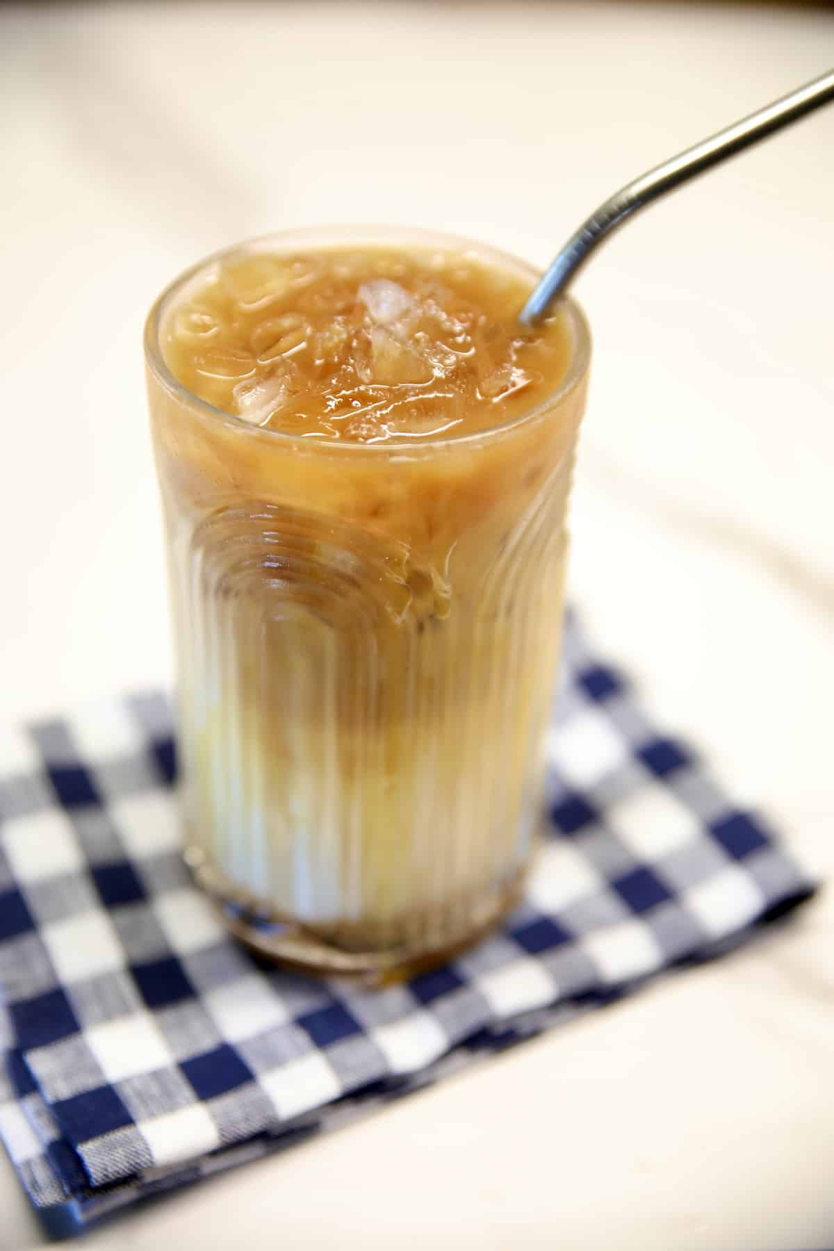 Caramel macchiato iced coffee in a glass with a straw.