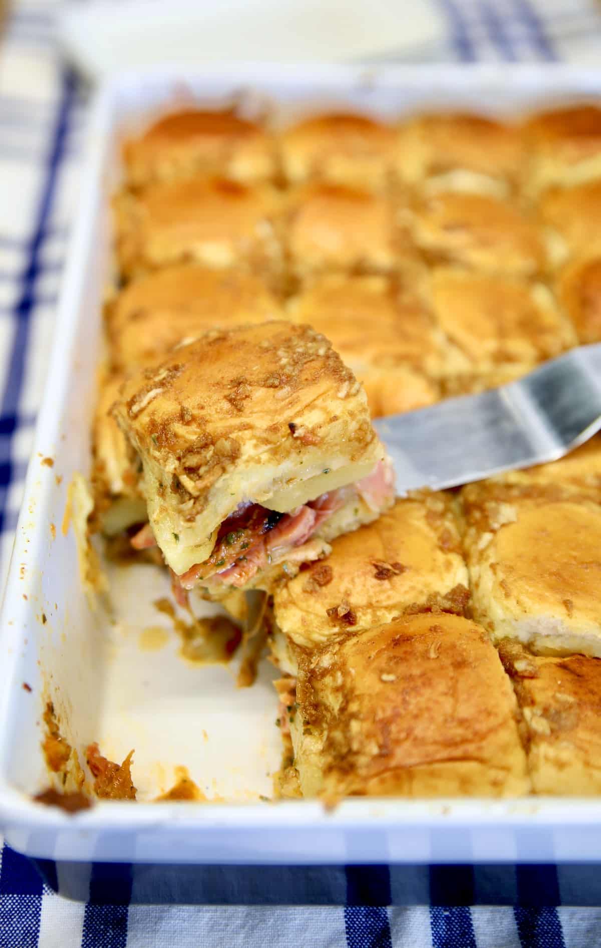 Pan of sliders, one on a spatula.