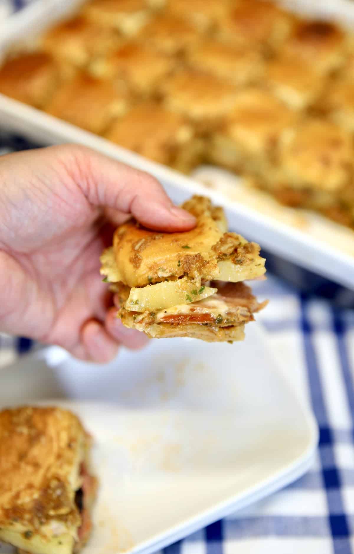 Ham and pineapple pizza slider held in hand.