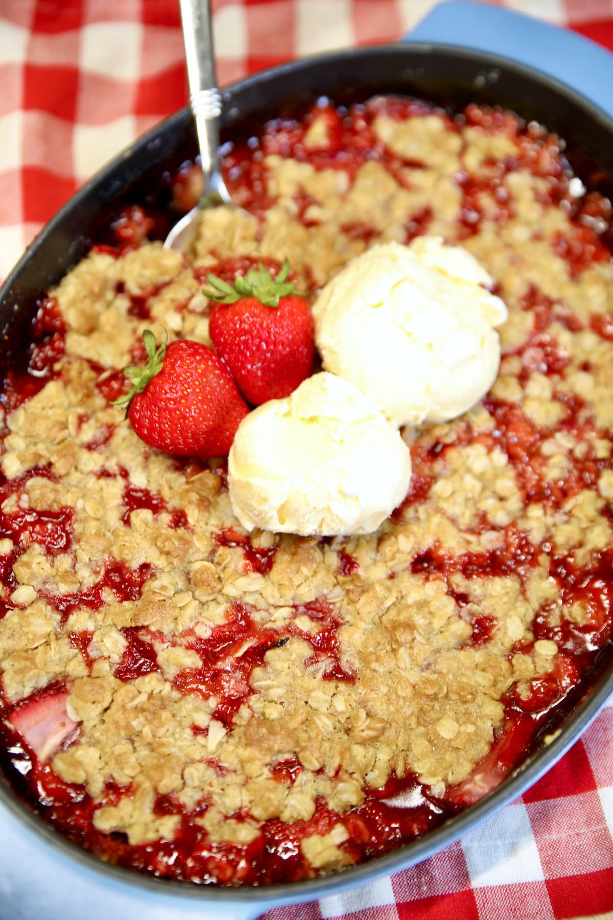 Strawberry Crisp in a pan with 2 scoops of vanilla ice cream.