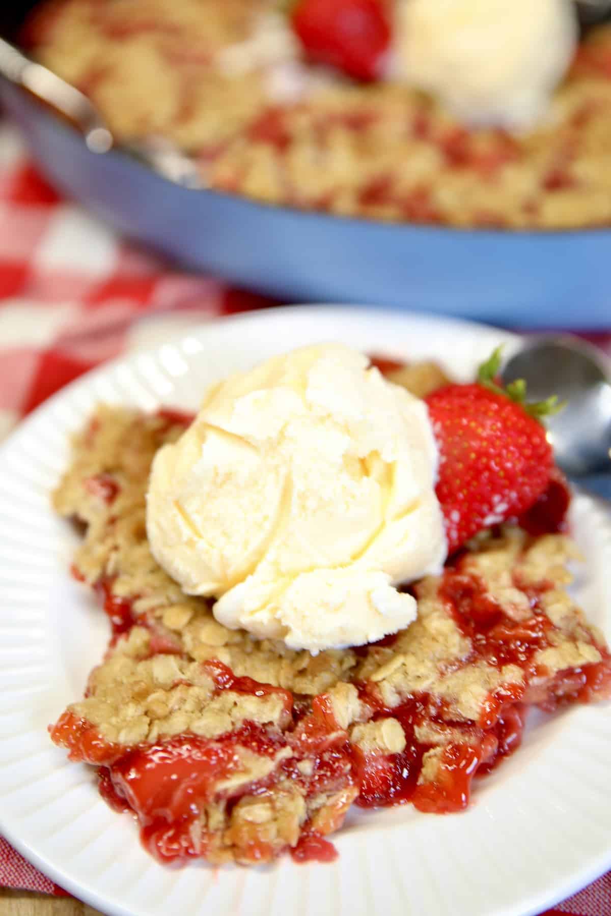 Plate of strawberry crisp topped with vanilla ice cream.