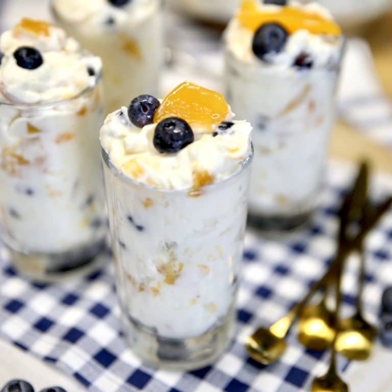 Peach blueberry no bake cheesecake in dessert glasses.