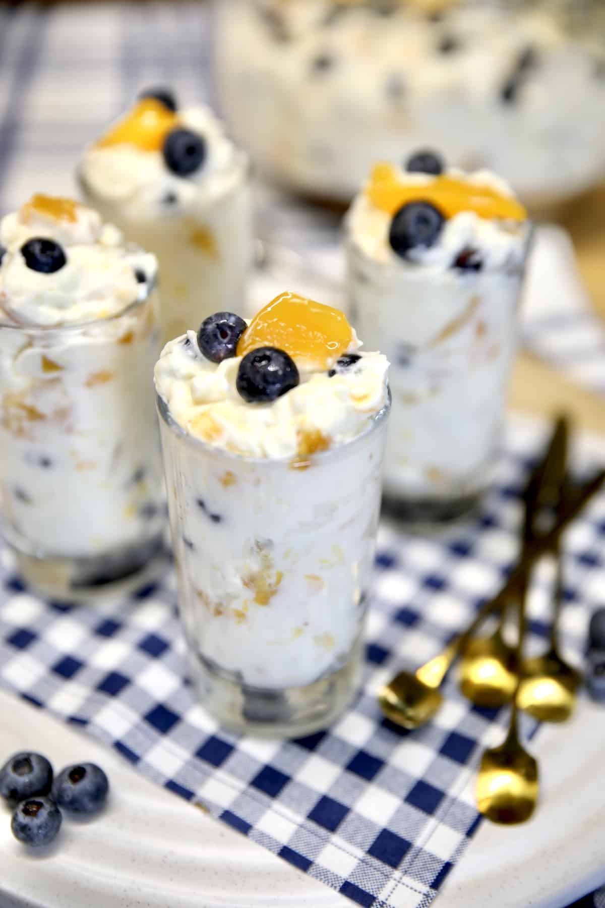 No Bake Cheesecake with peaches and blueberries in dessert glasses.