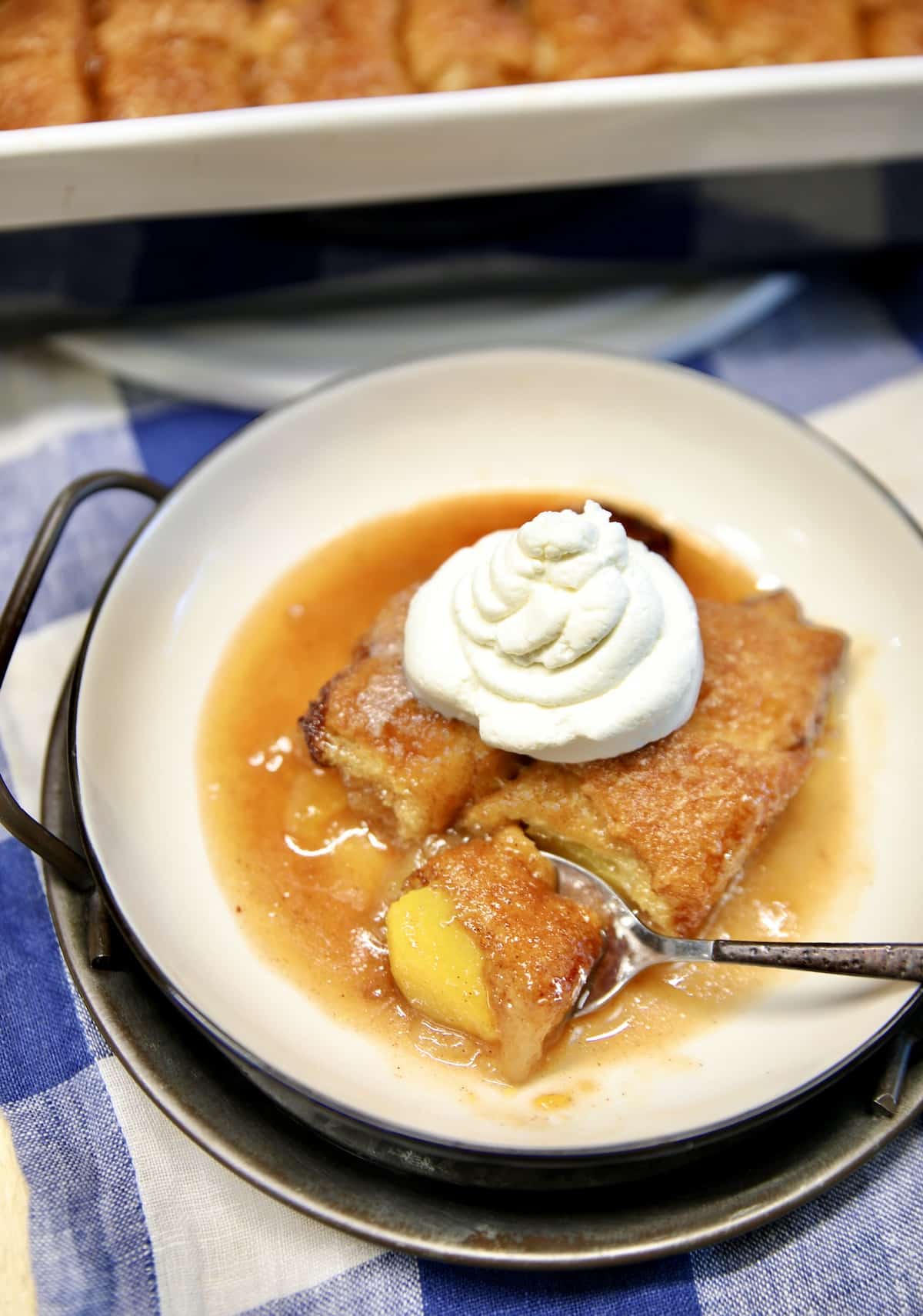 Peach dumplings with whipped cream in a bowl.