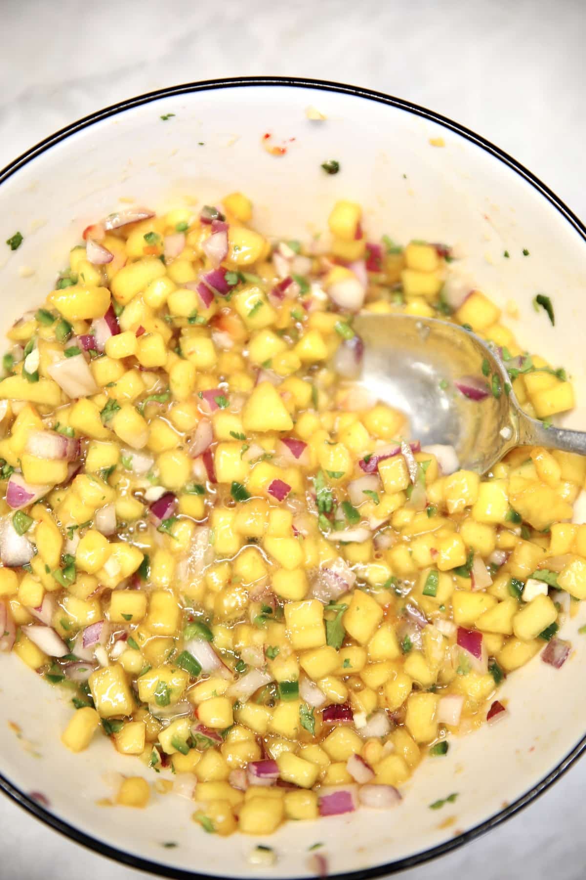 Peach salsa in a bowl with spoon.