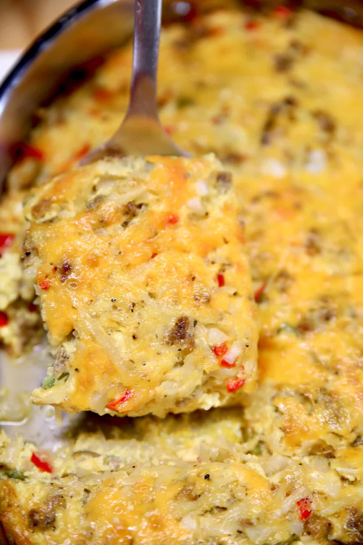 Hashbrown casserole with sausage on a spatula.