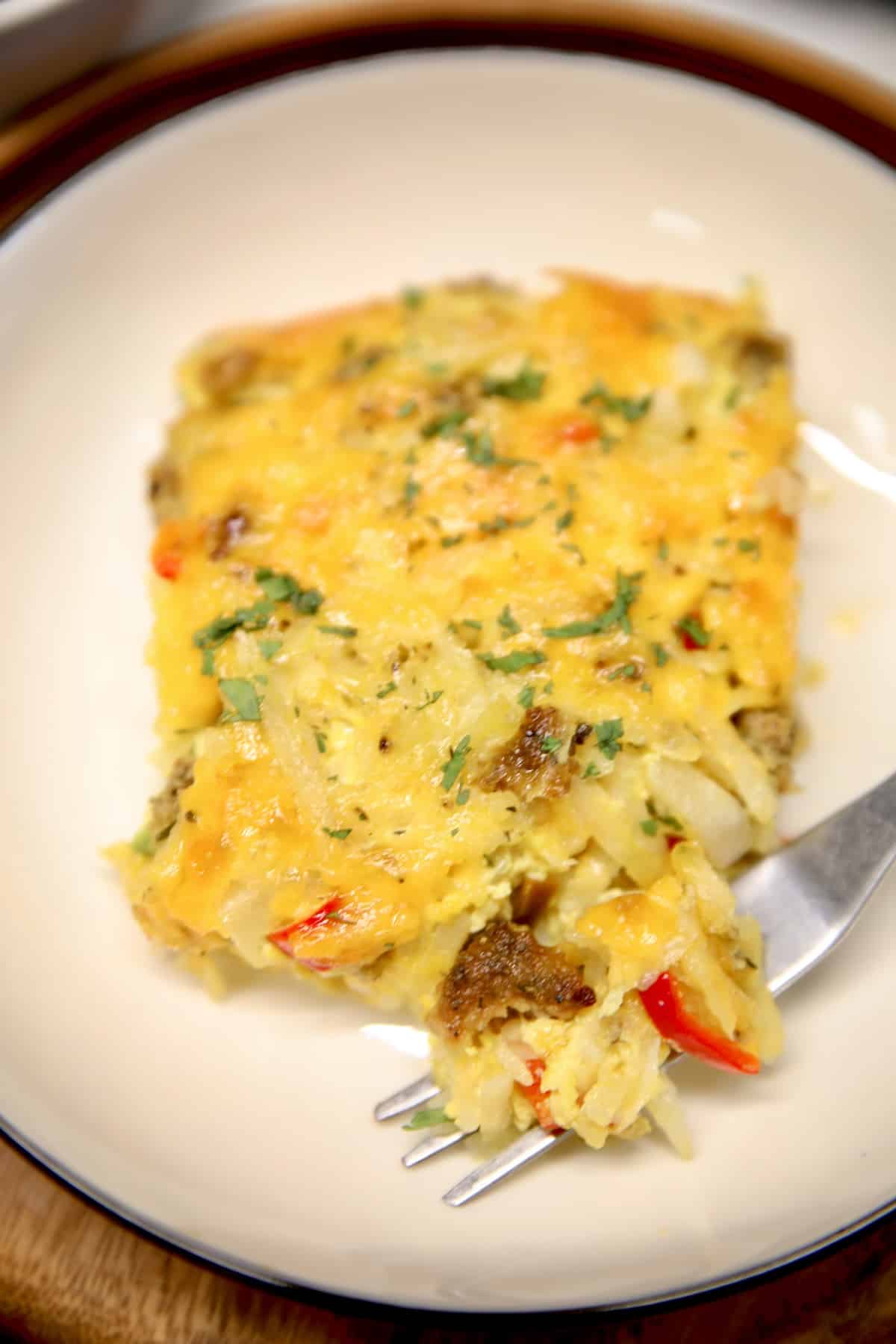 Breakfast casserole on a plate with fork.