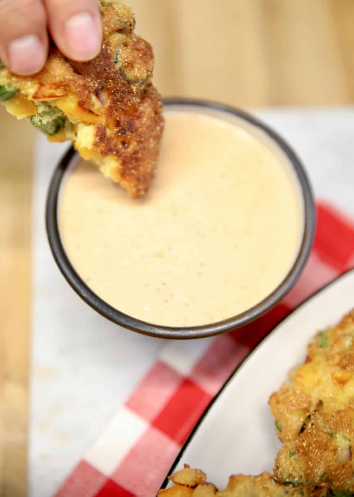 Okra patties dipping in sauce.