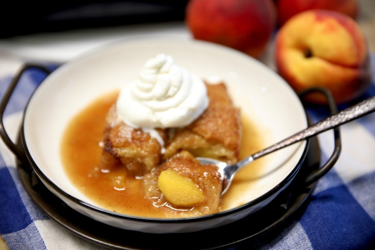 Peach dumplings with whipped cream in a bowl.