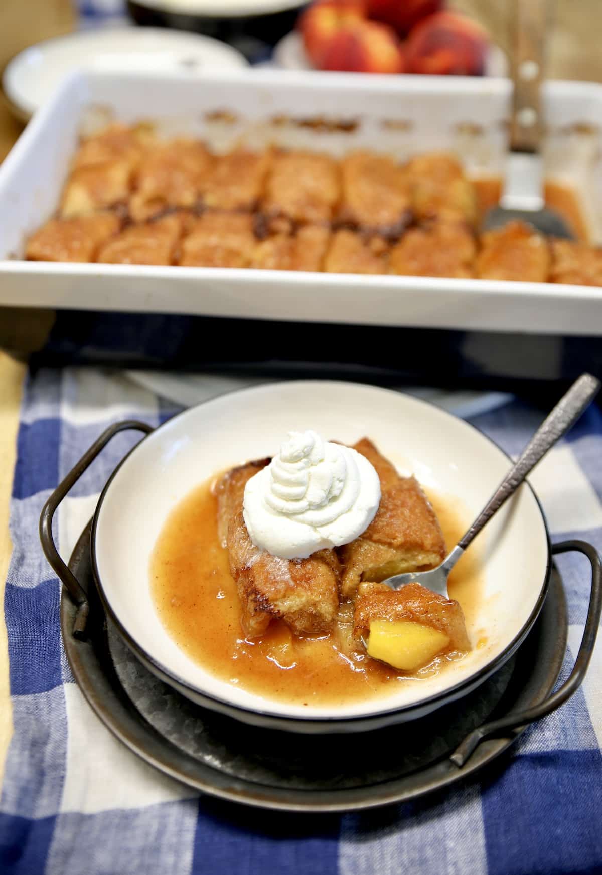 Bowl of peach dumplings with whipped cream.