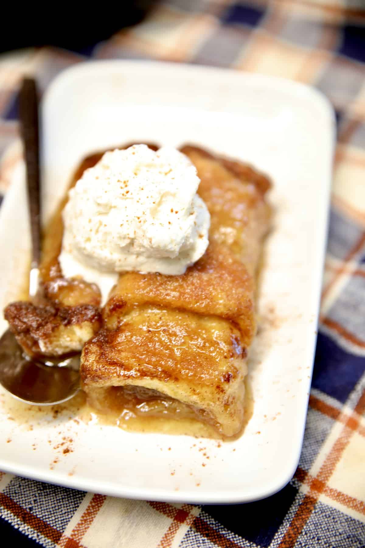 Crescent pumpkin dumpling on a plate with whipped cream and a spoon.