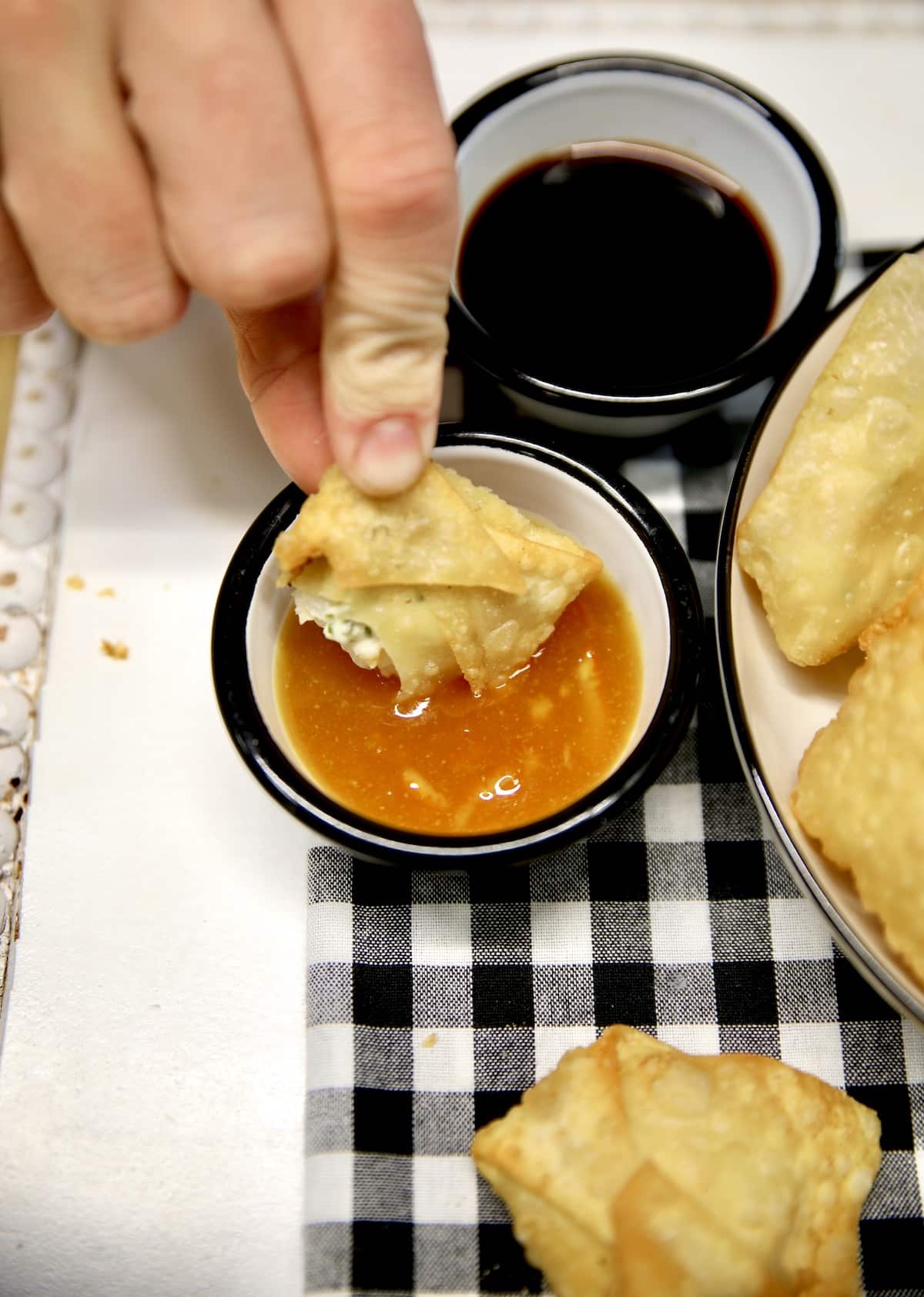 Shrimp rangoon dipping into orange dipping sauce.