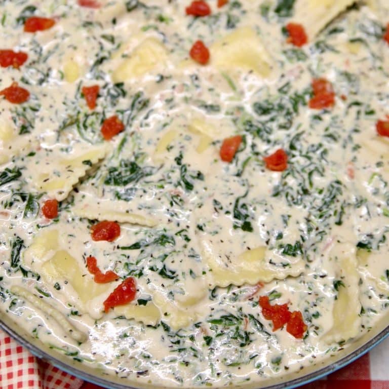 Pan of ravioli with cream sauce and spinach.