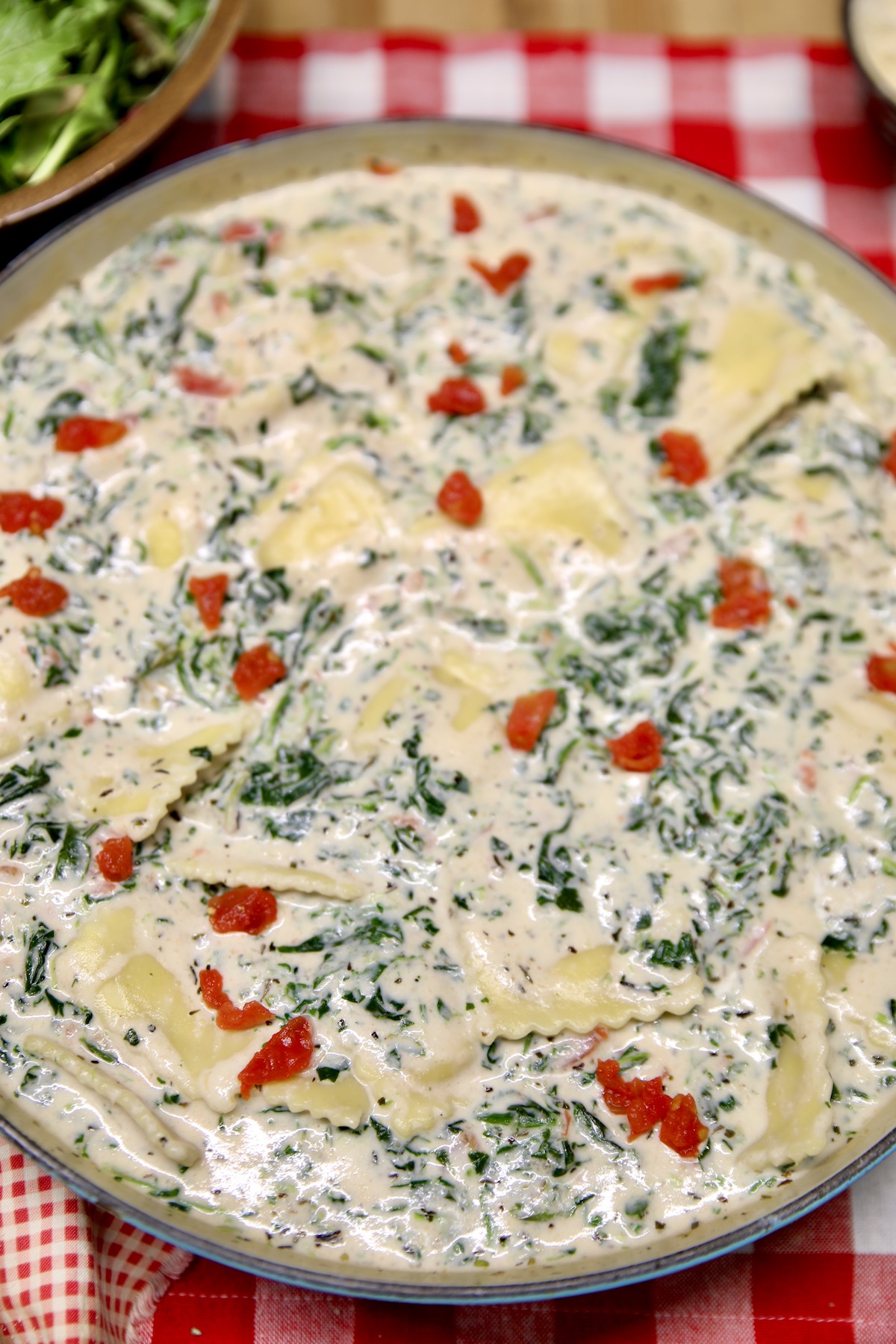 Pan of Tuscan ravioli with spinach and tomatoes.