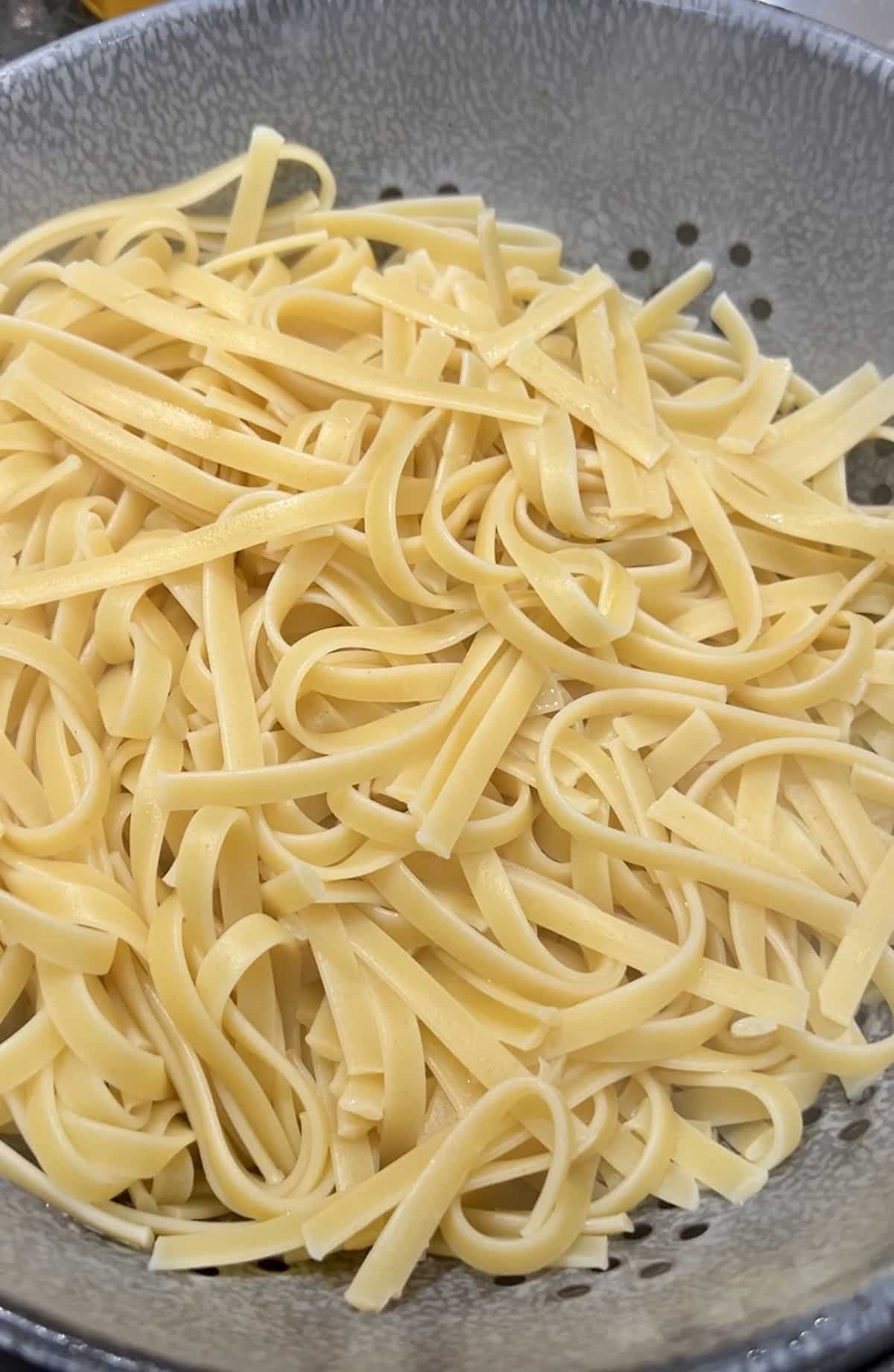 Fettuccine pasta draining in a colander.