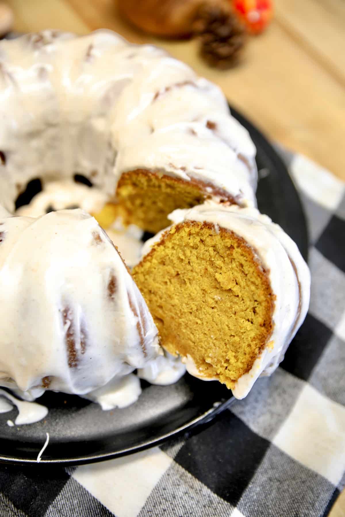 Pumpkin bundt cake with cream cheese icing, one slice cut out.