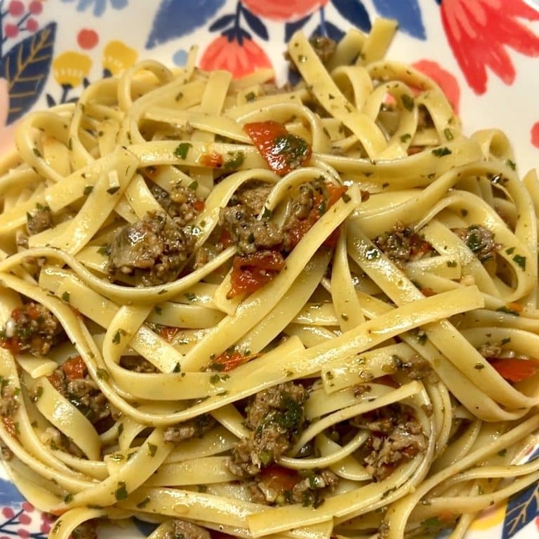 Bowl of fettuccine with tomatoes and sausage.