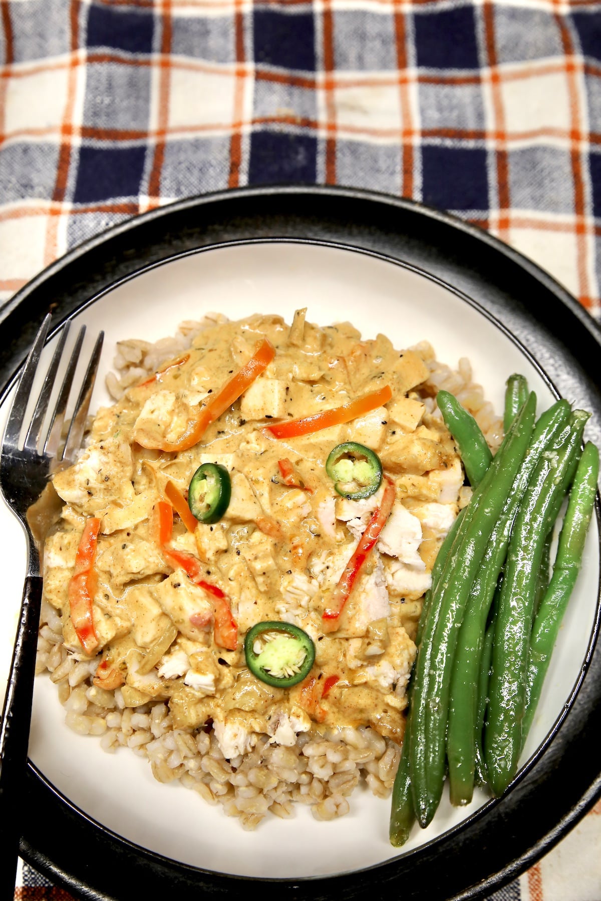 Plate of barley, chicken and cream sauce, green beans.