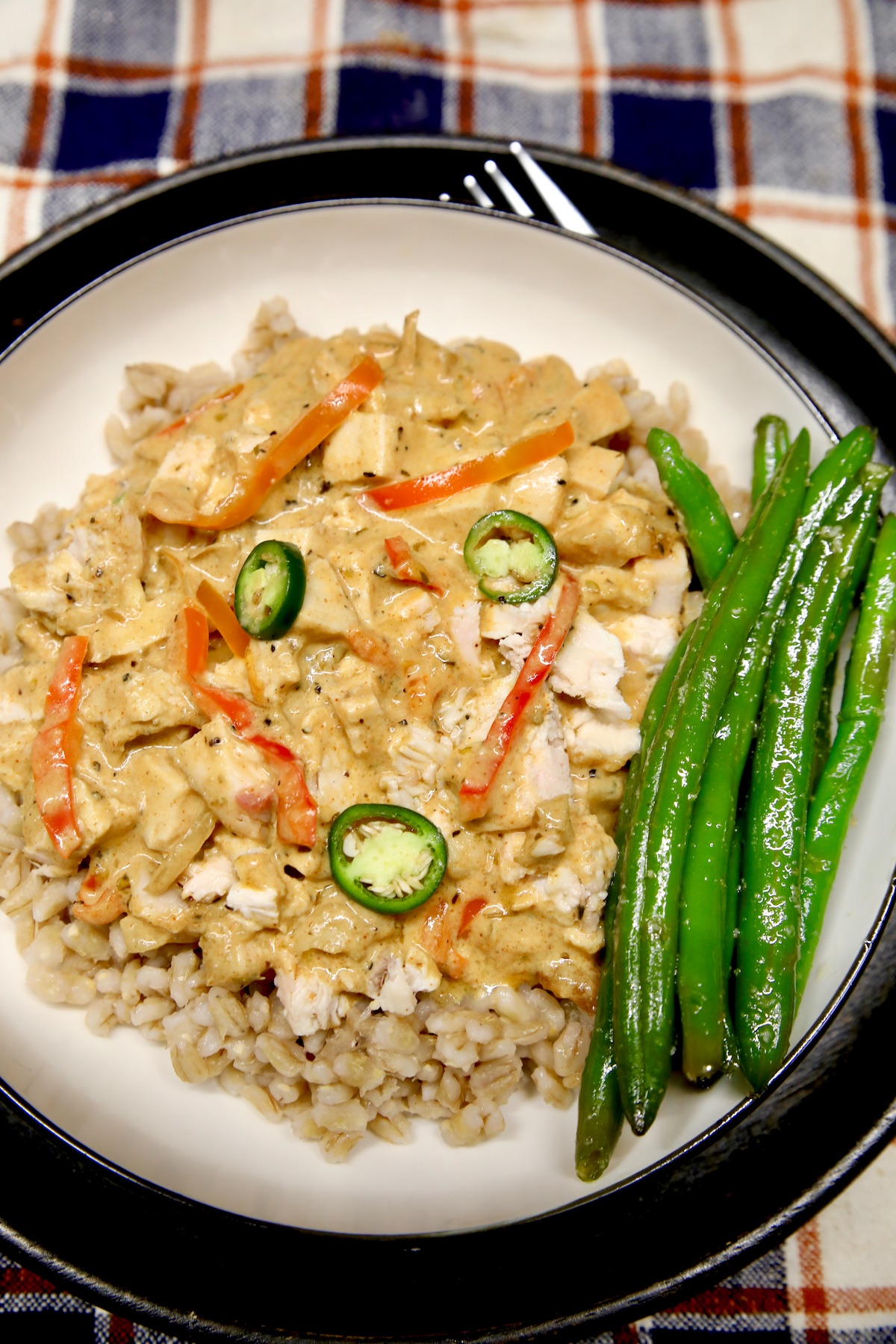 Plate of Cajun chicken over barley with green beans.