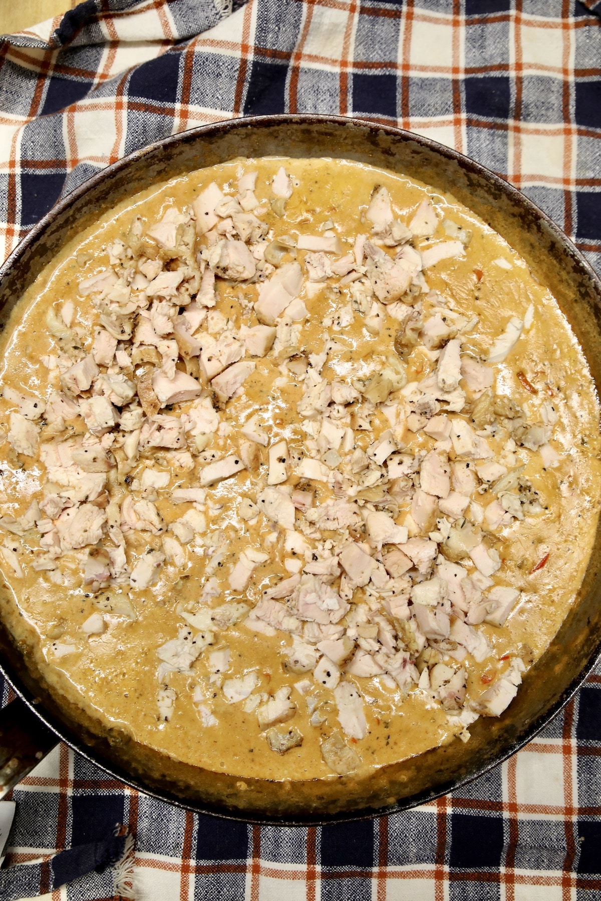 Adding chicken to Cajun cream sauce in a skillet.