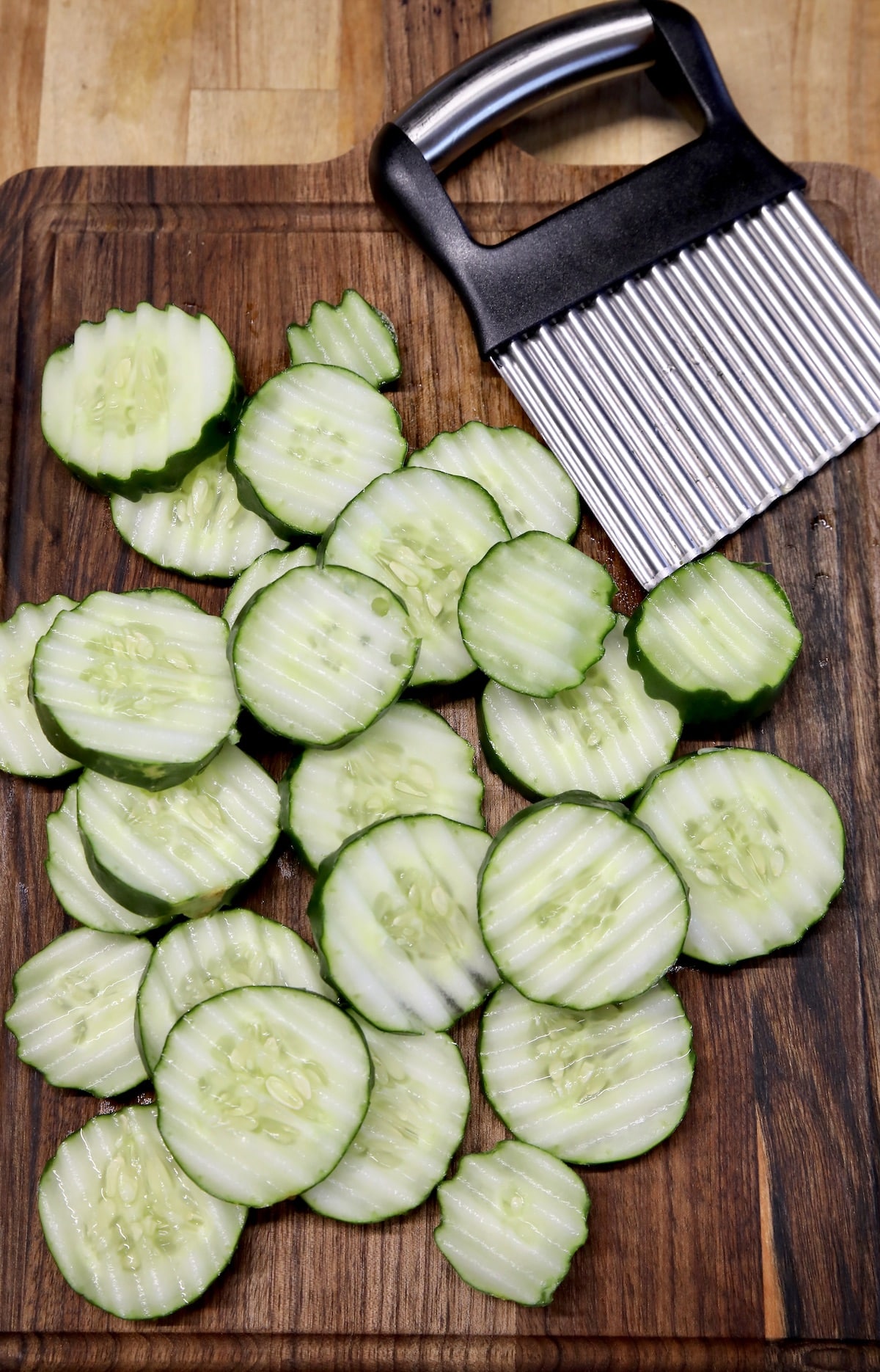 Sliced cucumbers with crinkle cutter on a board.