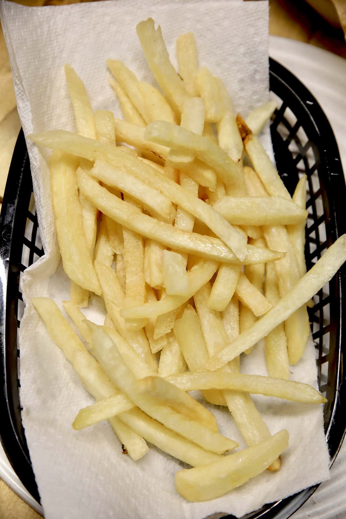 French fries on a paper towel lined plate.