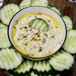 Bowl of dip with sliced cucumbers.