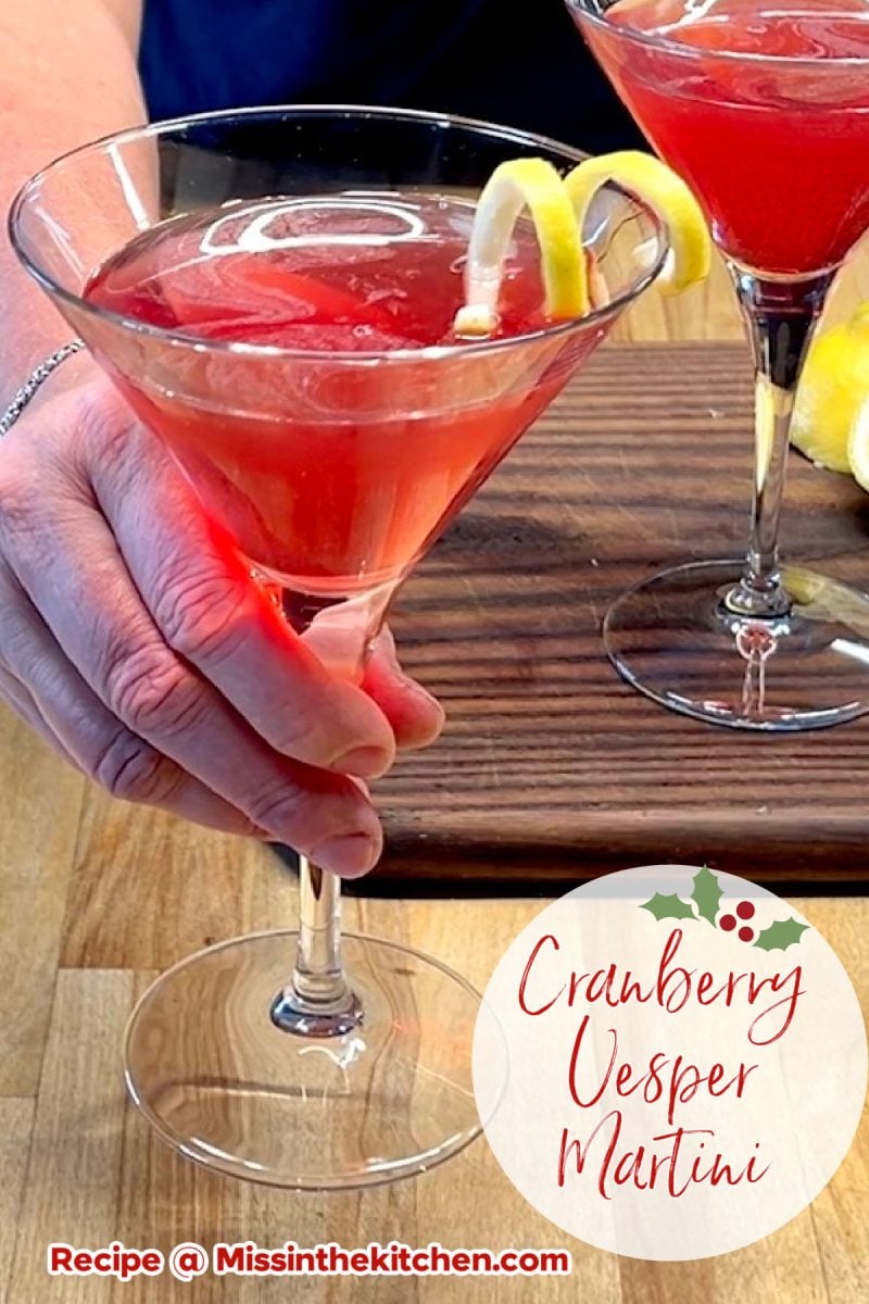 Cranberry vesper martini in a glass with lemon twist - text overlay.