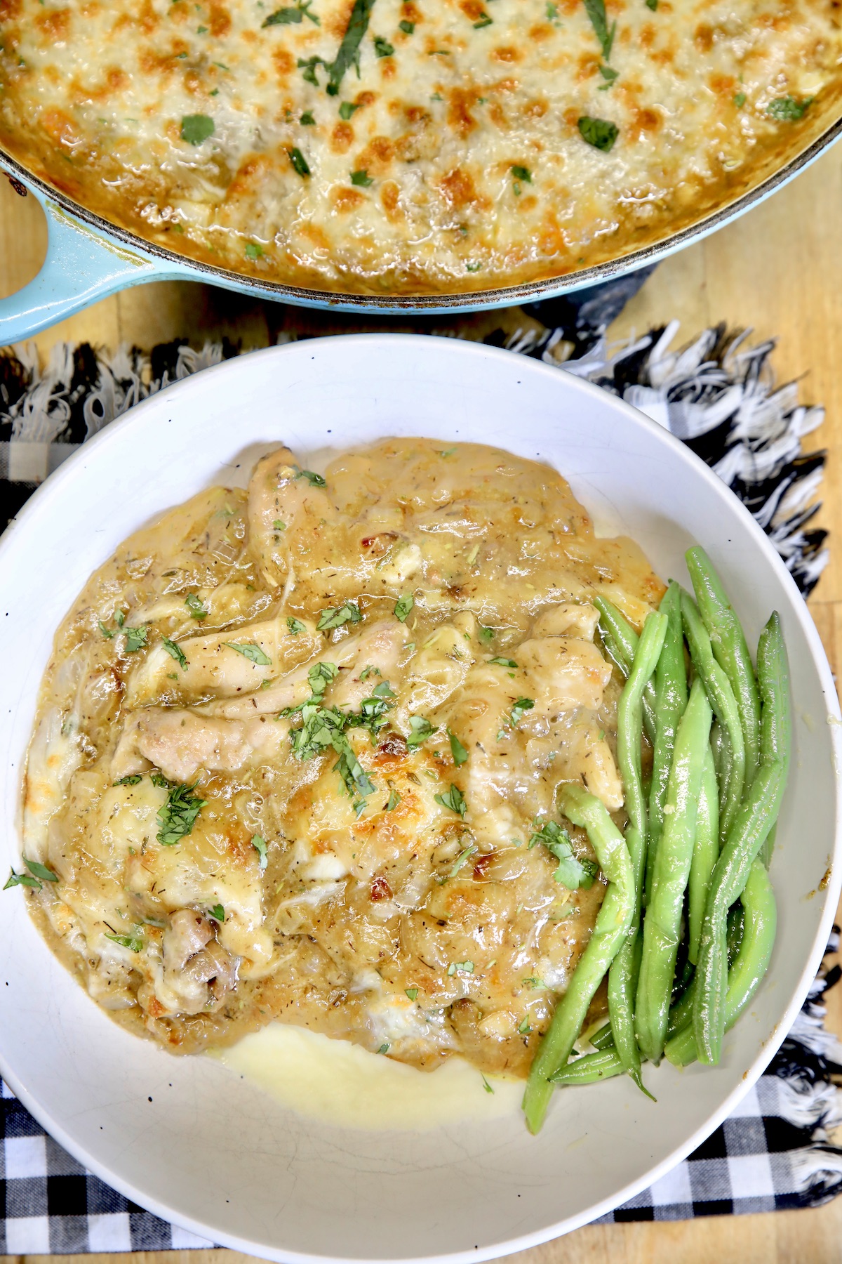 Bowl of mashed potatoes, chicken and onion gravy, green beans.