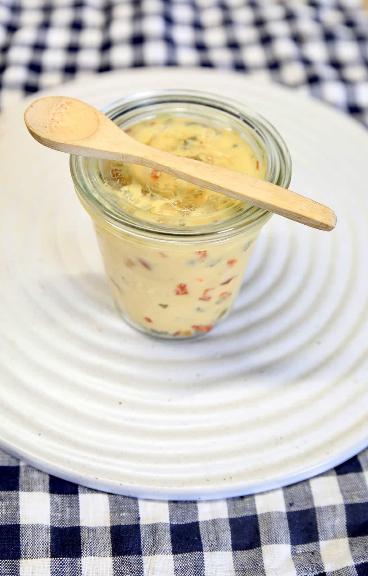 Jar with wood spoon of jalapeno cheese spread.