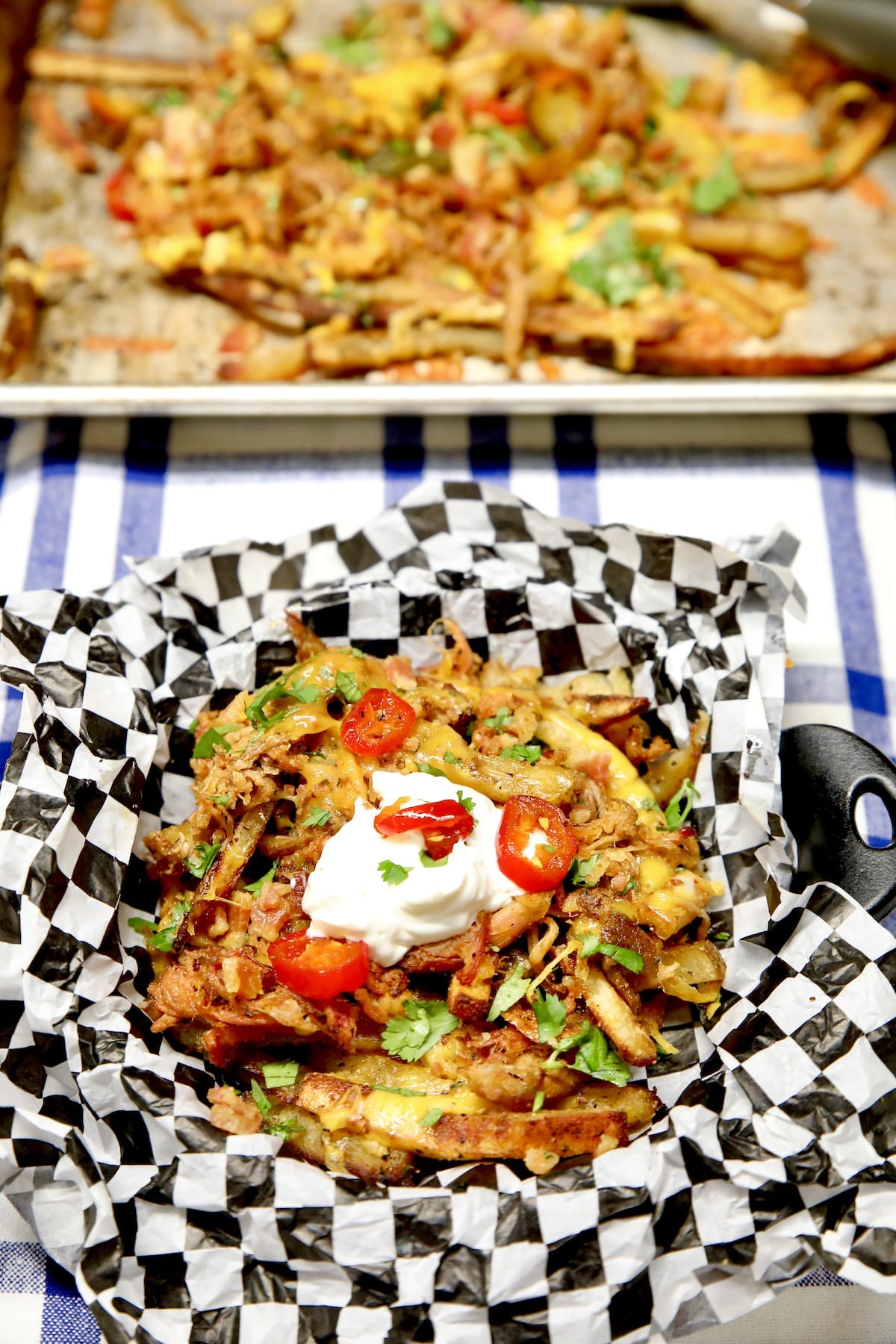 Loaded fries with pulled pork in a dish, sheet pan in background.