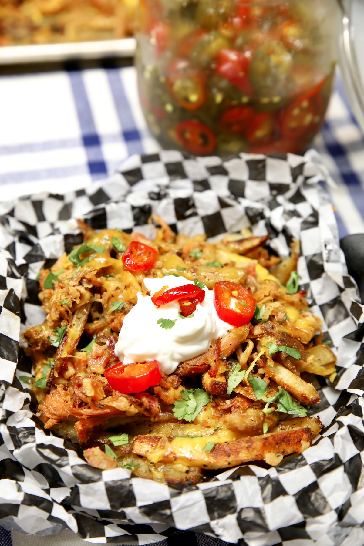 Plate of pulled pork fries with sour cream and jalapenos.